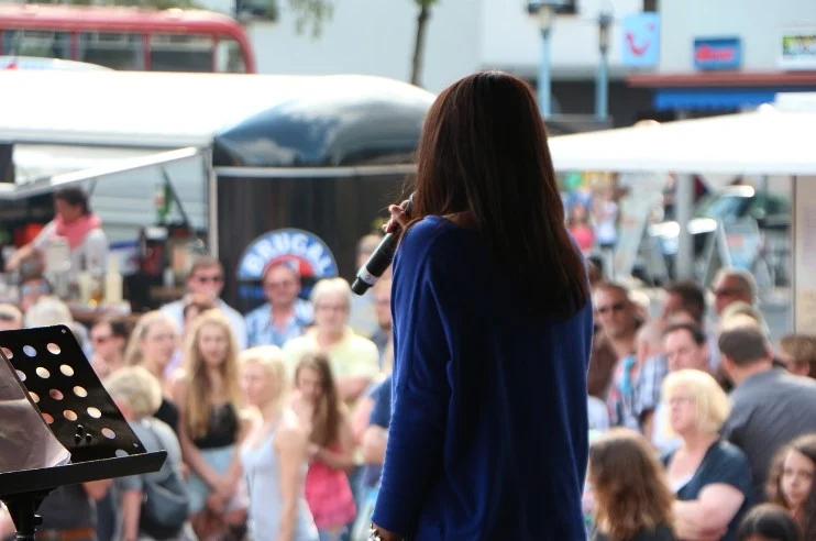 Woman with microphone infront of audience.