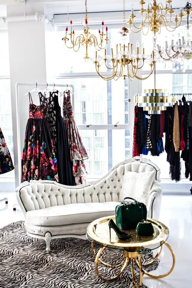 Store with white couch in foreground and clothing racks of dresses in background.