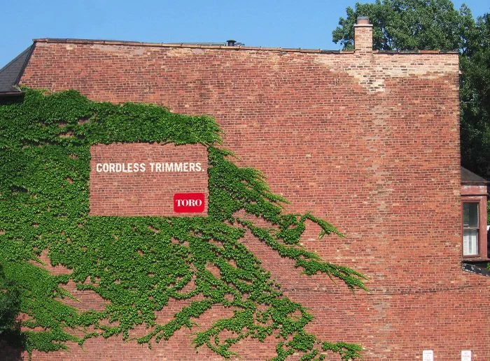 A guerilla billboard from the maintenance company Toro leveraging negative space on an ivy-covered wall.