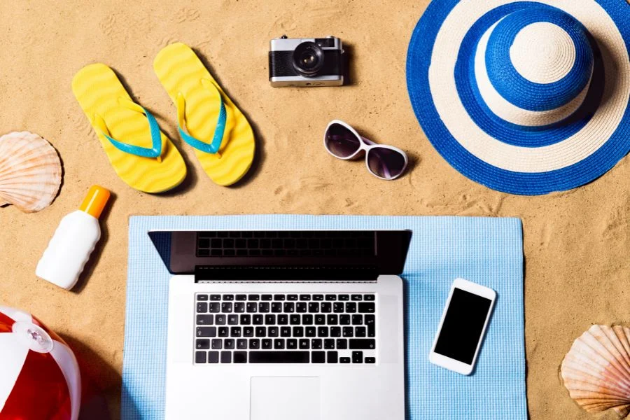 Summer vacation composition. Sandals, hat, laptop and smartphone.